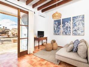 A living room with a sofa, a television, and a wall with tropical leaf prints. - Casa Antigua by Interhome (Santanyí)