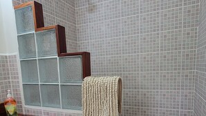 Une salle de bain avec une douche, des murs carrelés, un meuble-lavabo en bois et une porte de douche en verre.