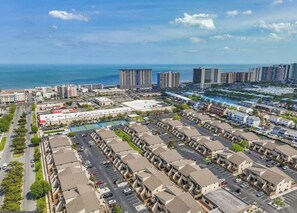 Une zone urbaine côtière caractérisée par des immeubles de grande hauteur, un port de plaisance et un complexe résidentiel doté d’un parking.