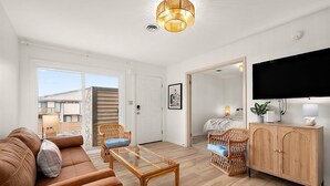 A modern living room with a sofa, chairs, a glass coffee table, a TV, and a cabinet. - Villa Condo with Amenities and Short Beach Walk (Ocean City)