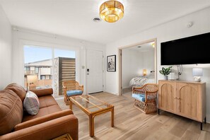 Un salon moderne comprenant un canapé, des fauteuils, une table basse en verre, un téléviseur et un meuble.
