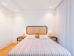 A modern bedroom with a large bed, two bedside tables with lamps, and a large window with curtains. - Apartment  by Interhome (Albufeira)