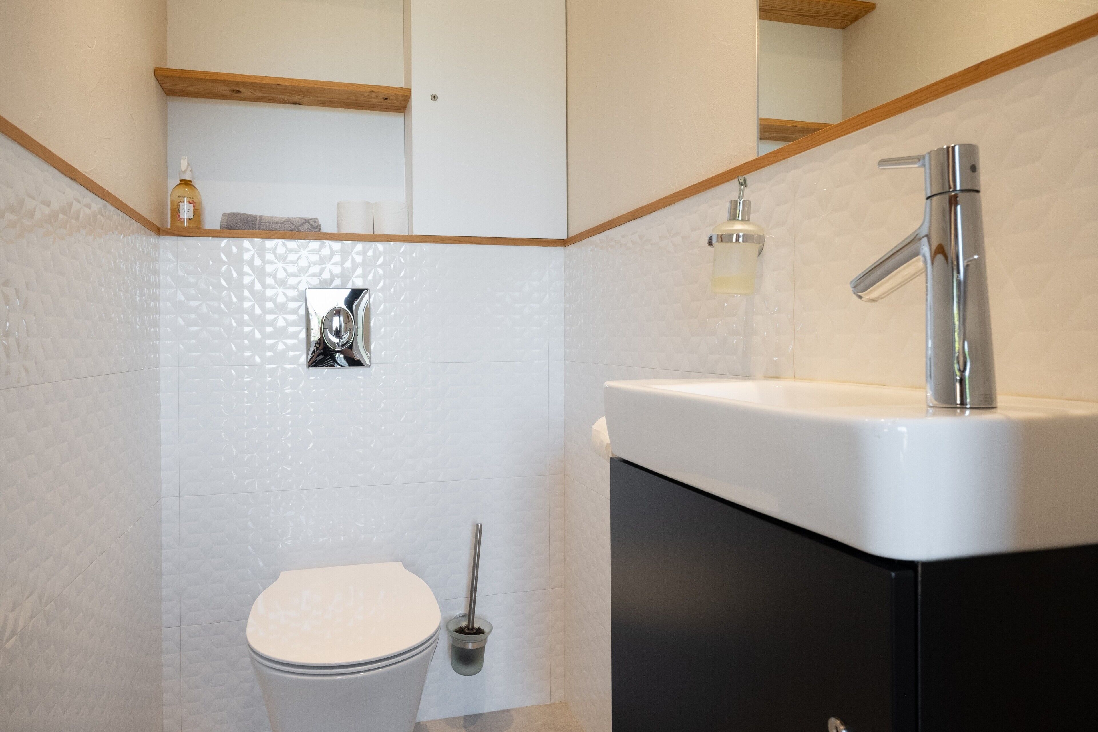 Une salle de bain comprenant des toilettes, un bidet, un lavabo et un miroir.