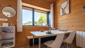 A wooden interior with a dining table, chairs, a mirror, and a window with a view. - Duplex Cottage Between Lake and Mountains in the High Vosges (Saulxures-sur-Moselotte)