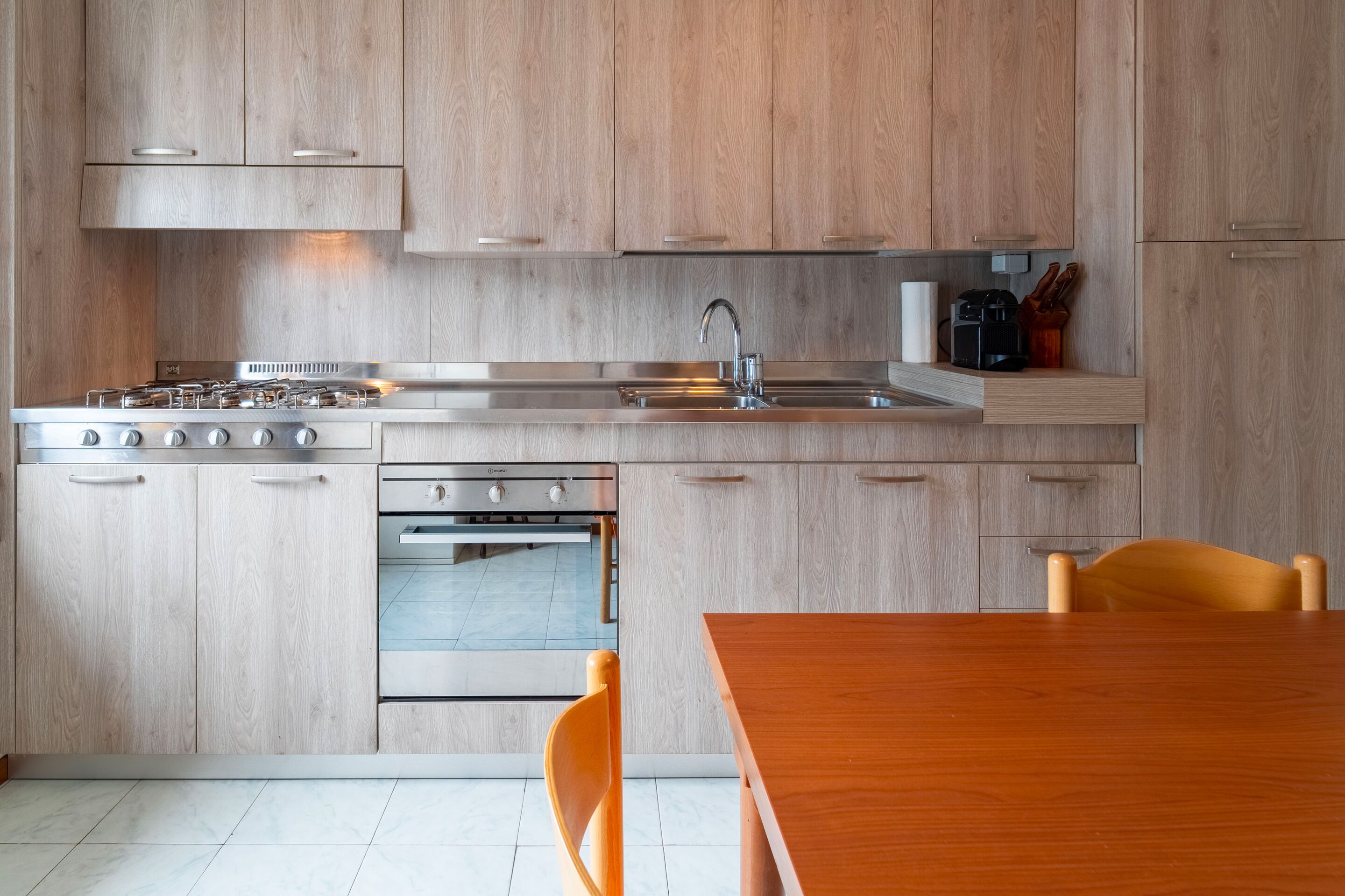 Eine moderne Küche mit Holzschränken, Edelstahlgeräten und einem Holztisch.