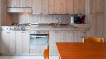 Eine moderne Küche mit Holzschränken, Edelstahlgeräten und einem Holztisch.