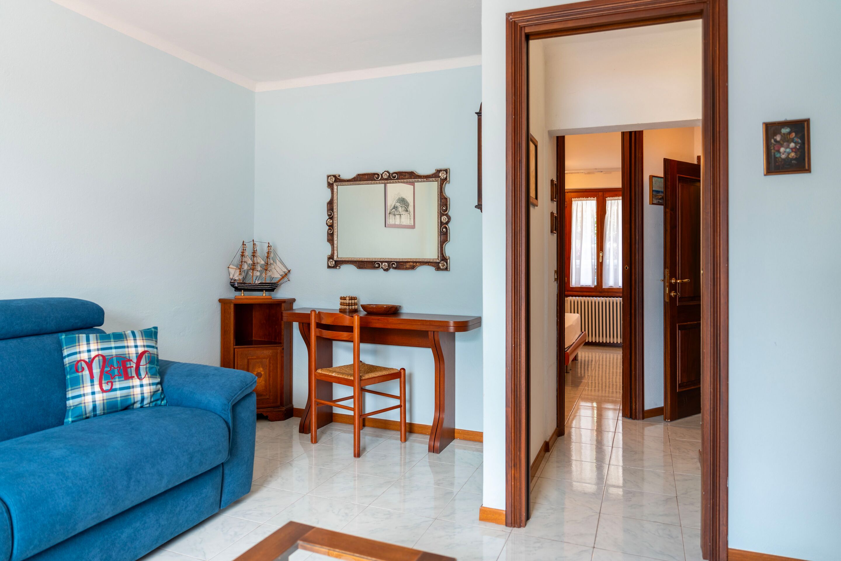 Una sala de estar con un sofá azul, una mesa de comedor de madera y una silla.