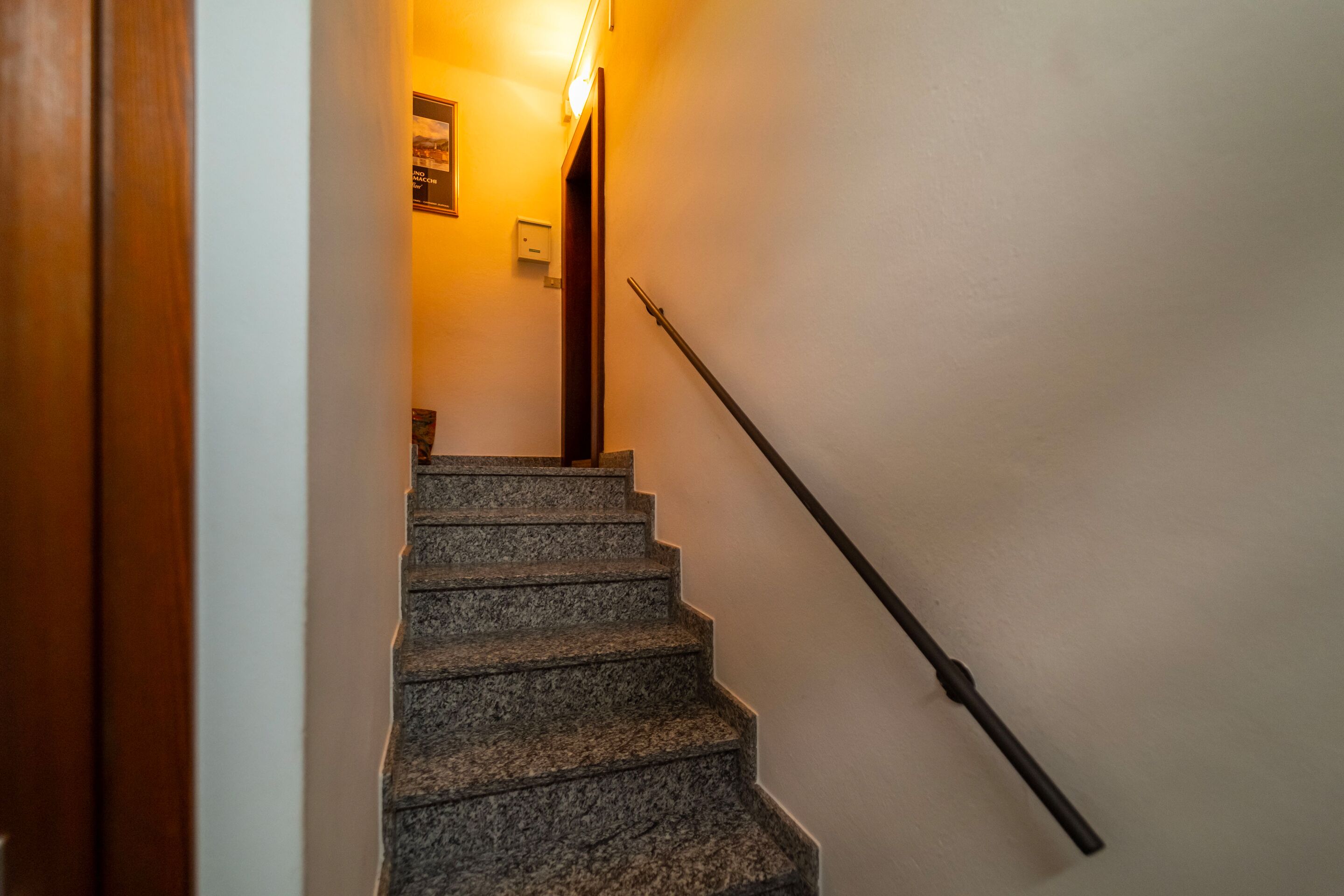 Un escalier avec une rampe, un cadre de porte en bois et un luminaire fixé au mur.
