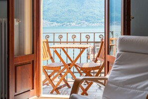 Ein Holztisch und -stühle auf einem Balkon mit Blick auf einen See und Berge.