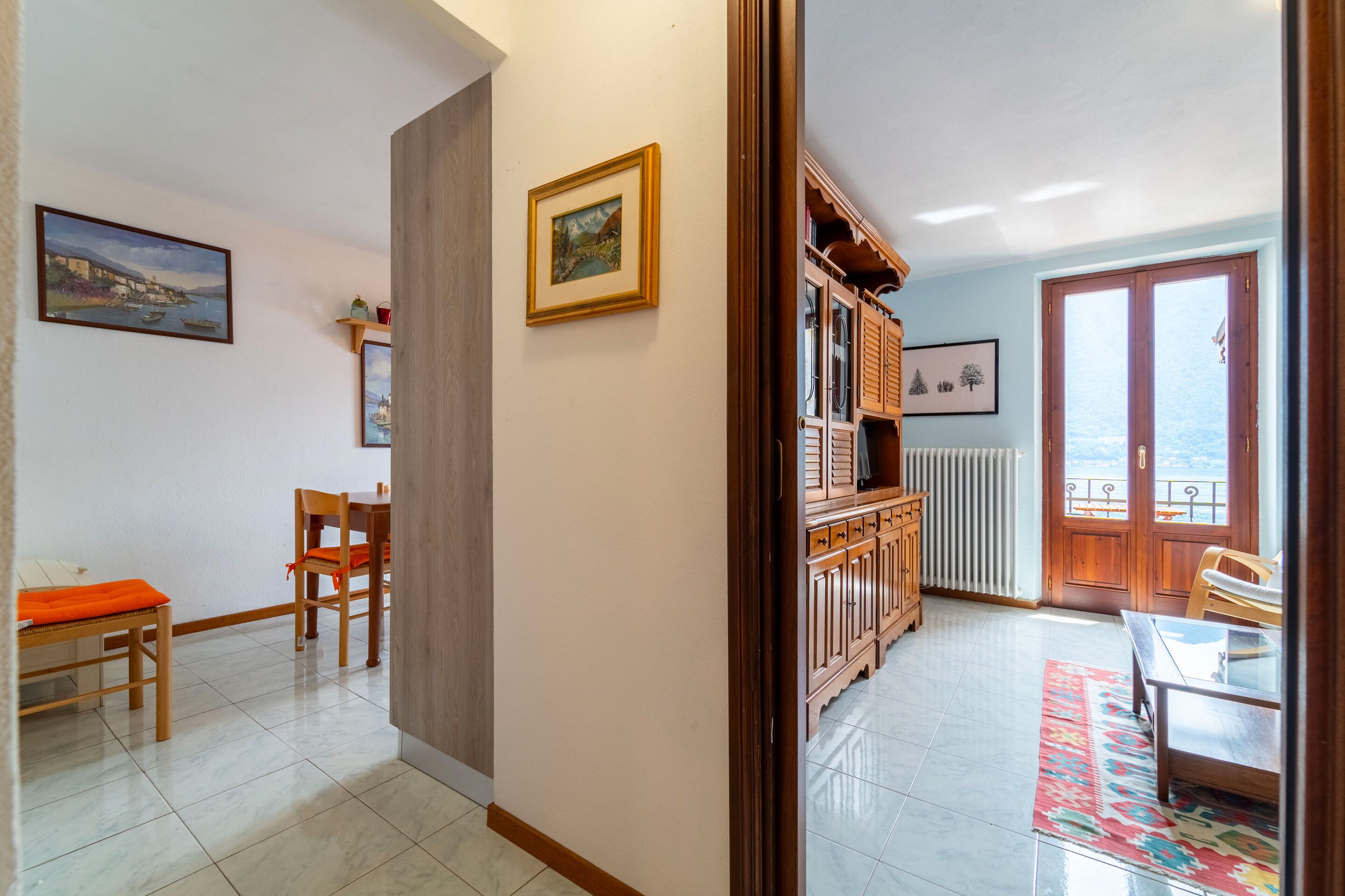 A dining area with wooden furniture, a view to the outside, and a door leading to a balcony.