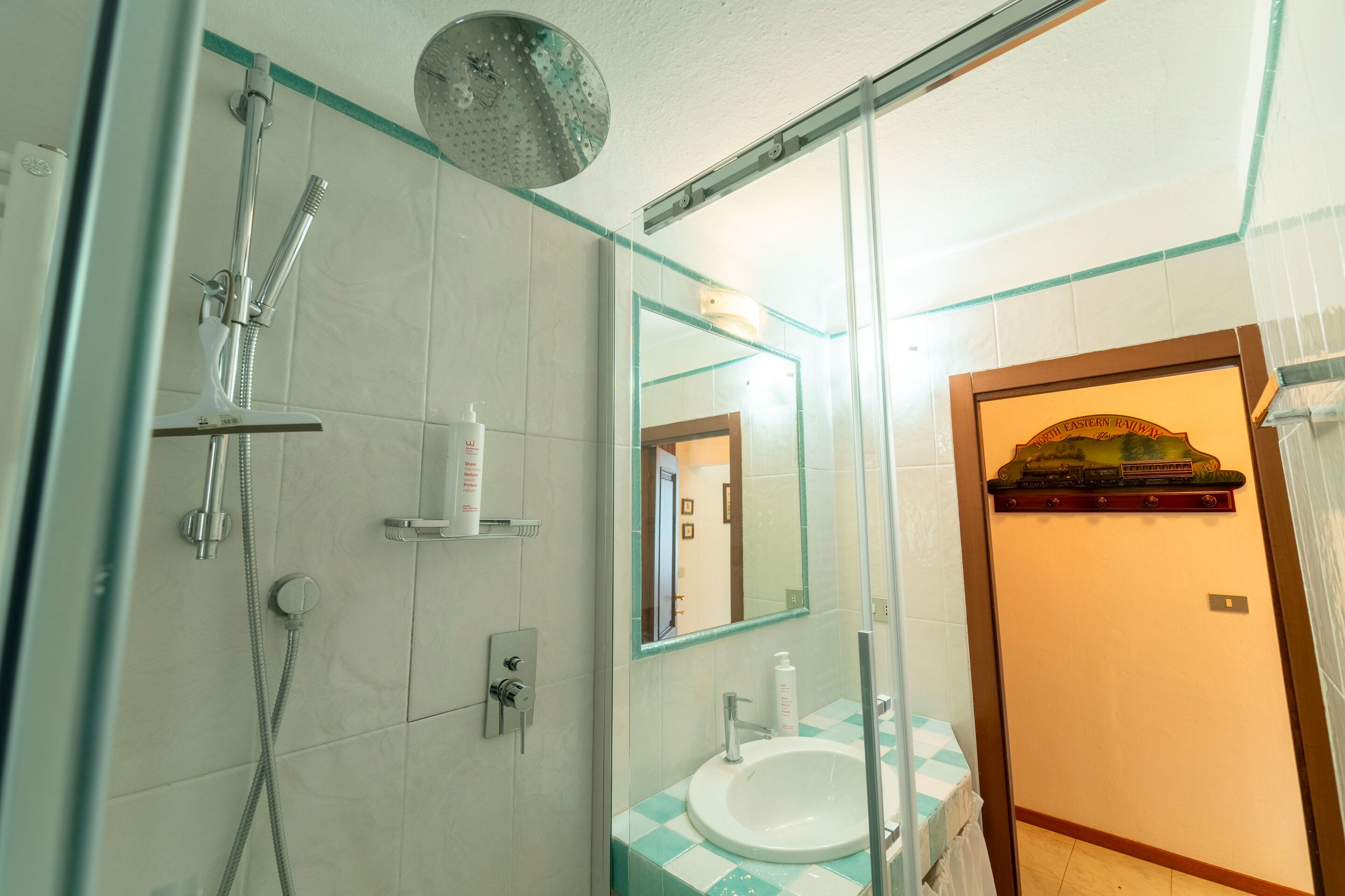 A bathroom with a shower, sink, and mirror.