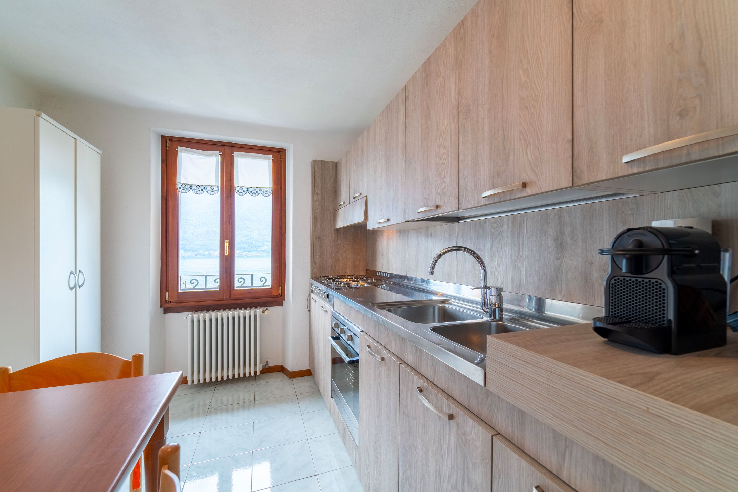 A kitchen with wooden cabinets, a stainless steel sink, and a coffee machine.