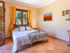 A bedroom with a bed, curtains, a painting, and a bookshelf. - Can Molino by Interhome (Cala Figuera)