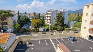 Eine mehrgeschossige Parkgarage mit deutlich ausgewiesenen Stellplätzen, einer kleinen Kiosk und Blick auf umliegende Gebäude und Grünflächen.