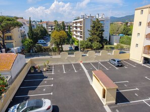 Eine mehrgeschossige Parkgarage mit deutlich ausgewiesenen Stellplätzen, einer kleinen Kiosk und Blick auf umliegende Gebäude und Grünflächen.