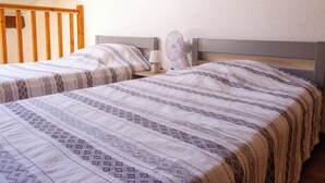 Ein Schlafzimmer mit zwei Betten, einem Nachttisch, einer Lampe und einem Deckenventilator.