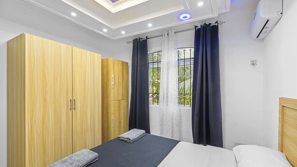 A bedroom with a bed, a wardrobe, a skylight, and an air conditioning unit. - Jaddoo Apartment at Azeer Residence (Grand-Baie)
