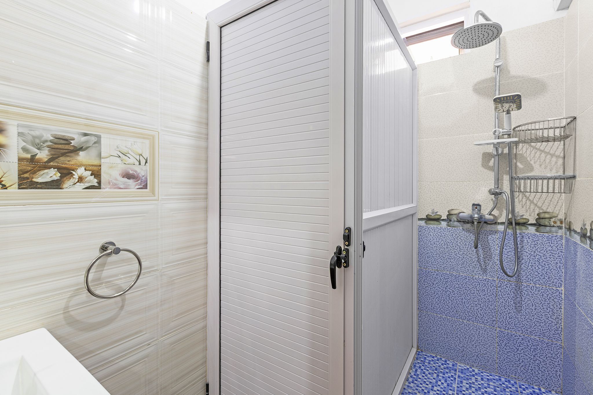 A bathroom with a shower, a towel ring, and a sink.