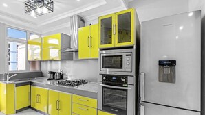 A modern kitchen with yellow cabinets, stainless steel appliances, and a built-in oven. - Jaddoo Apartment at Azeer Residence (Grand-Baie)
