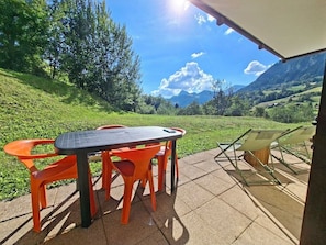 An outdoor patio with a table and chairs, a sunshade, and a view of a mountainous landscape. - Skiing, terrace, swimming pool: ideal apartment (Flumet)