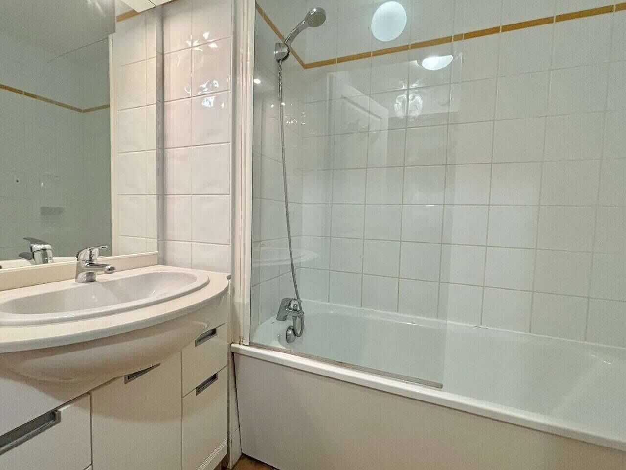 A bathroom with a sink, mirror, and a shower enclosure.