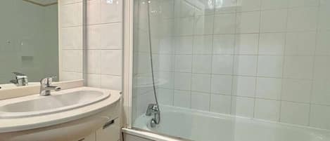 A bathroom with a sink, mirror, and a shower enclosure.