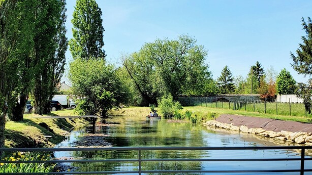 Een terras met buiten zitplaatsen, een vijver en uitzicht op een park.