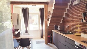 Een kleine keuken met een magnetron, een spoelbak en een houten aanrecht.