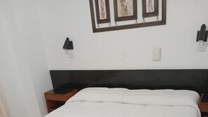 A neatly made bed with white linens and two towels arranged in a floral pattern. - Cadi Palace (Mar del Plata)
