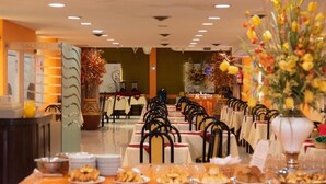 A dining area with tables set for service, a reception desk, and a decorative plant arrangement. - Cadi Palace (Mar del Plata)