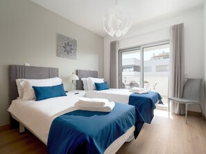 Ein modernes Hotelzimmer mit zwei Betten, einer Sitzecke und Blick auf die Stadt.