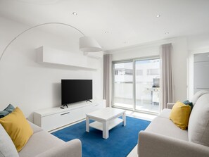 A modern hotel room with a flat-screen TV, a white coffee table, and two sofas with cushions. - Lagos town centre apartment by Interhome (Lagos)