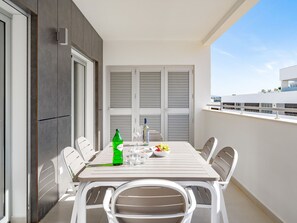 Ein Balkon mit Tisch für zwei Personen, komplett mit Flasche, Gläsern und einer Obstschale.