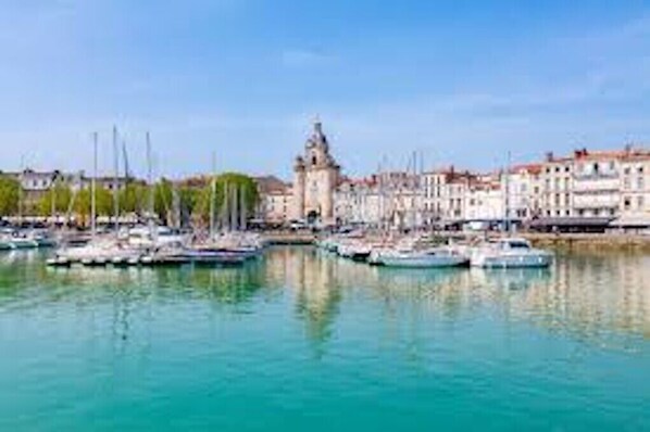 A marina with boats, a prominent tower, and buildings along the waterfront. - Studio with terrace in the old port of La Rochelle (La Rochelle)