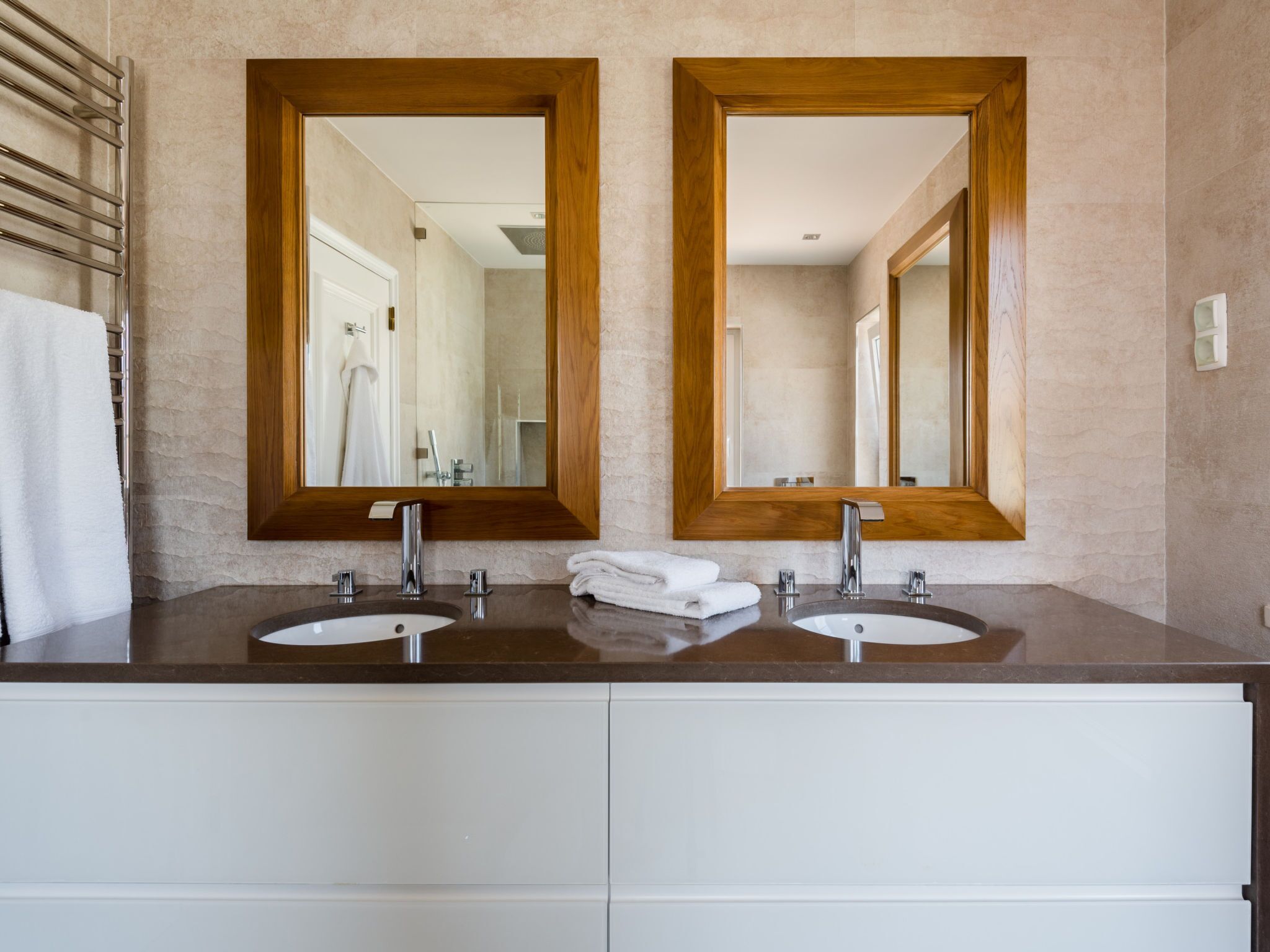 A bathroom with two sinks, a mirror, and a towel rack.