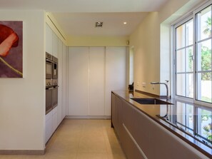 Eine moderne Küche mit Backofen, Spüle aus Edelstahl und einem Fenster mit Blick auf Grünflächen.