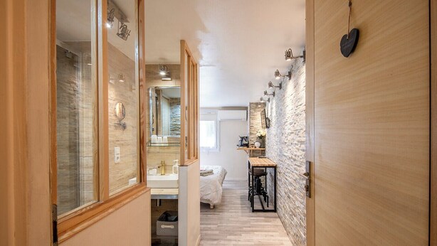 A narrow hallway with a wooden floor, a bed, a small table, and a mirror. - Studio near Old Port, Panier and Station (Marseille)