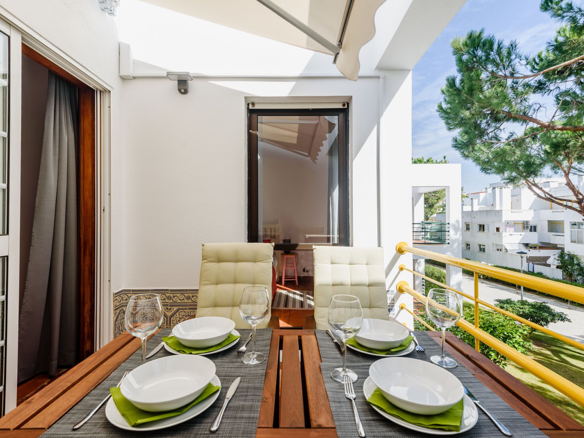 Een balkon met een eethoek, inclusief een tafel, stoelen en uitzicht op de omliggende gebouwen.