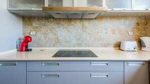 Een moderne keuken met een ingebouwde oven, een rode waterkoker, een broodrooster en een marmeren spatwand.
