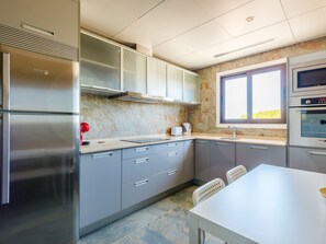 A modern kitchen with stainless steel appliances, grey cabinets, and a window providing natural light. - Apartment  by Interhome (Albufeira)