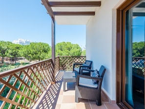 A balcony with wicker furniture and a view of trees and buildings. - Apartment  by Interhome (Albufeira)