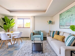 A modern living room with a dining area, a sofa set, a coffee table, and a large window with curtains. - Apartment  by Interhome (Albufeira)