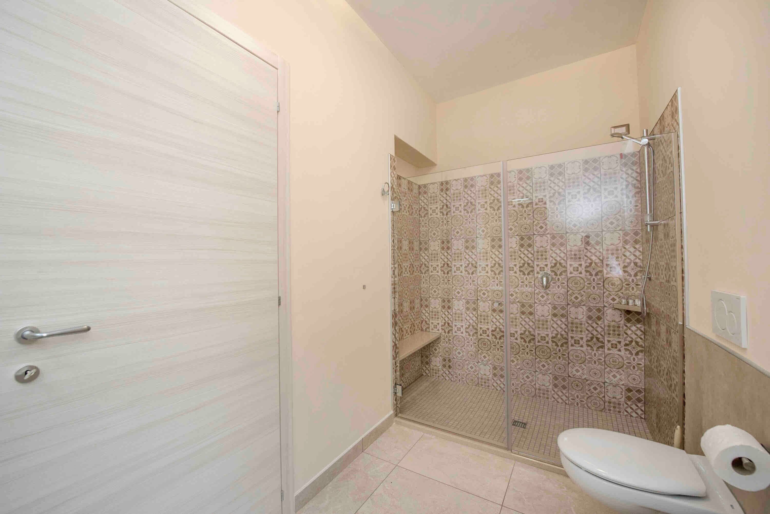 Une salle de bain avec des toilettes, une douche et une porte dotée d’une poignée.