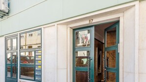 A building with a cobblestone street entrance, numbered 87, and a green door with a window. - Apartment  by Interhome (Lisbon)