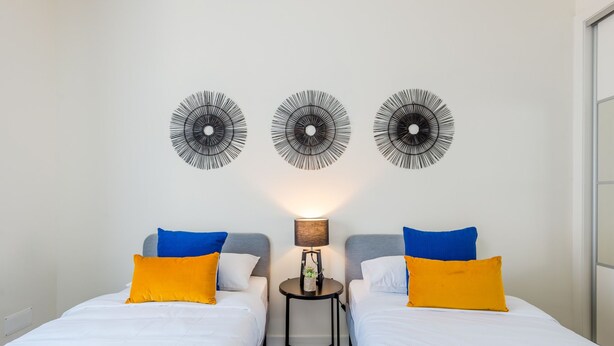 A hotel room with two beds, a small table with a lamp, and three wall-mounted decorative items. - Apartment  by Interhome (Lisbon)