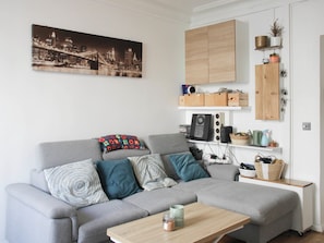 Ein modernes Wohnzimmer mit grauem Sofa, einem Couchtisch und einem Stadtbild an der Wand.
