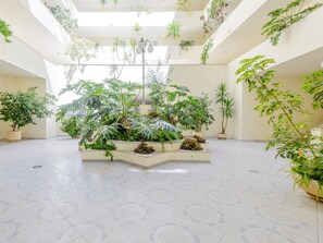 A spacious atrium with multiple levels of greenery, including large potted plants and hanging plants, and a patterned floor. - Apartment  by Interhome (Vilamoura)