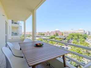 Ein Balkon mit Tisch und Stühlen, einer Obstschale und Blick auf die Stadt.