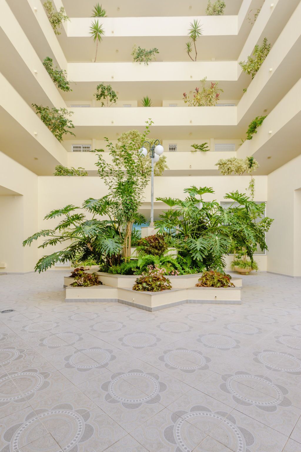 A multi-level atrium with tiered planters containing various plants and a central light fixture.