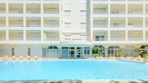 Uma área de piscina de hotel com vários níveis de varandas, um espaço de estar coberto e vista desobstruída da piscina.